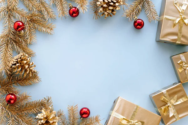 青いクリスマスや新年の背景、赤いクリスマスのおもちゃ、フラットレイ、挨拶テキストのための空のスペースと黄金のクリスマスプレゼントや黄金のモミの枝の平らな組成。クリスマスの概念. ストックフォト