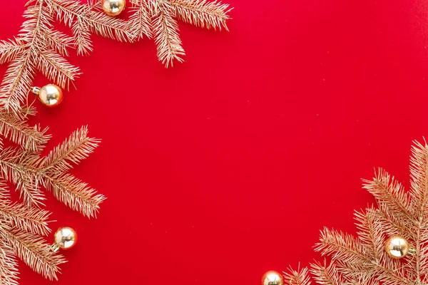 Piros karácsonyi vagy újévi háttér, egyszerű összetétele Arany fenyő ágak és karácsonyi játékok, Flatlay, üres hely üdvözlő szöveg. Stock Fotó