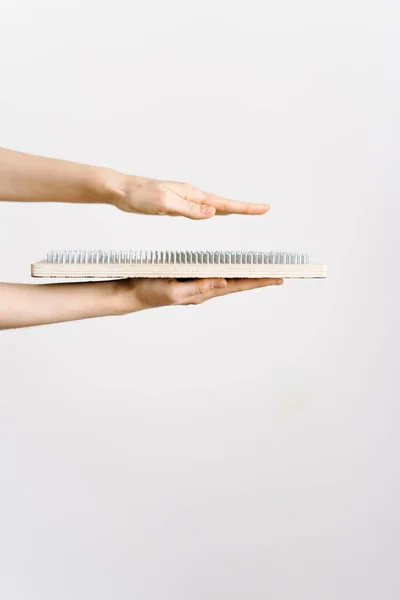 Avrupalı görünümlü bir kadın galvanize tırnaklı tahta bir tahtayı tutuyor ve elini sadhu tahtasının tepesine koyuyor. Kendini geliştirme eğilimi. Yoga konsepti