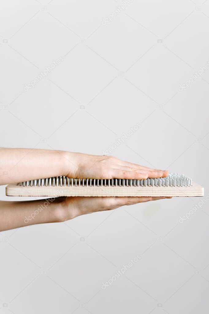 a woman of European appearance holds a wooden board with galvanized nails and puts her hand on top of the nails of the sadhu board. the trend of self-development. the concept of yoga