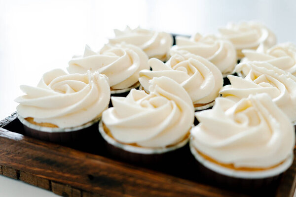 свежеиспеченные кексы с клубничной начинкой и белым сливочным сыром на деревянном подносе. Свежеиспеченные кексы на десерт.