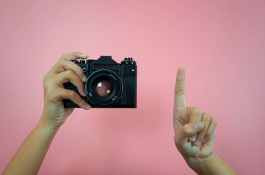 Pembe arka planda kadın ellerinde eski bir kamera.