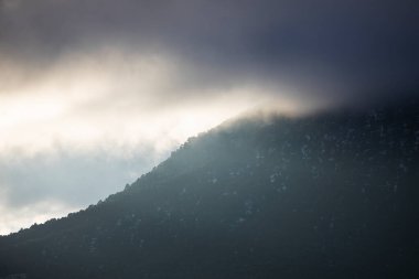 Gün batımında bir sürü ağaç, kar ve sis olan dağlar.