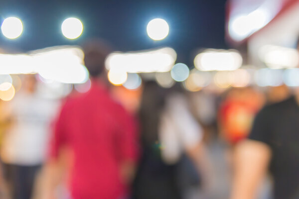 Абстракция смуглых людей, гуляющих по ночному торговому центру
