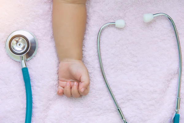 Orvosi műszerek sztetoszkóp újszülött baba lány kezét — Stock Fotó