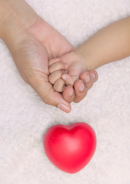 Yeni doğan bebek anne hurma ile kırmızı kalp elinde — Stok fotoğraf