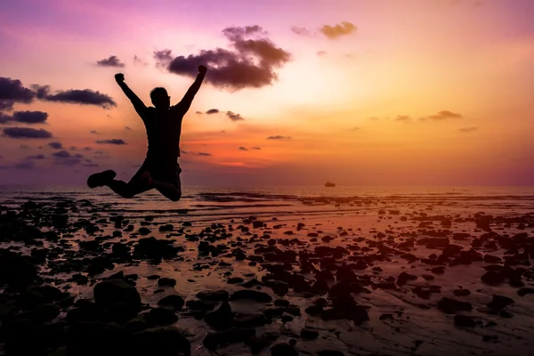 Hombre Salto feliz con las manos en alto al atardecer en la playa — Foto de Stock