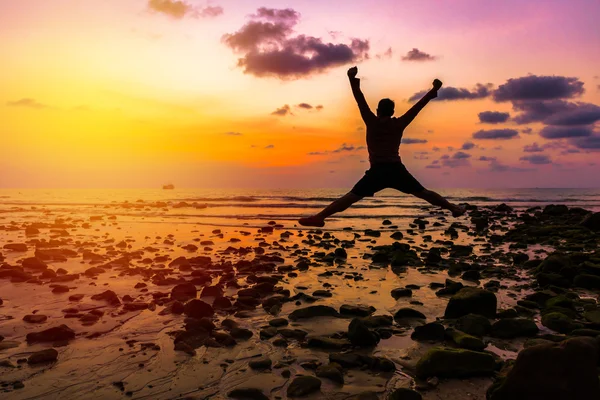 man Happy jump with his hands up during sunset at the beach