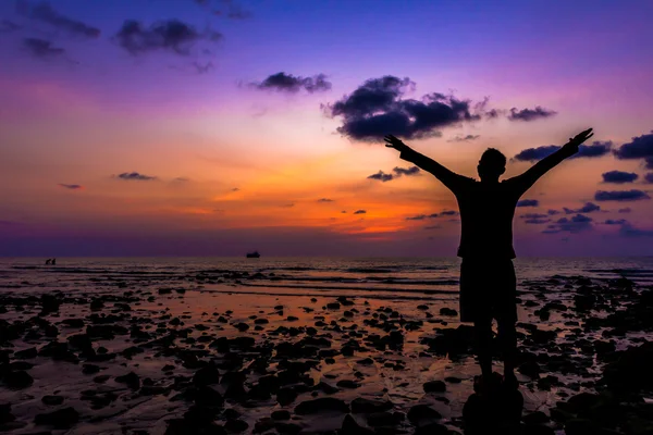 Silhouette del viaggiatore con le mani alzate al tramonto sull'oceano — Foto Stock