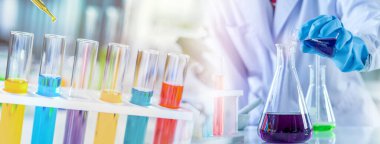 Banner, ekipman ve bilim deneyleri yapan bilim adamı, laboratuvar bardakları araştırma için kimyasal sıvı içeriyor ya da laboratuvar ortamında bir numuneyi test tüpüne koyup analiz ediyor.