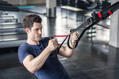 Spor salonunda karın kaslarını güçlendirmek için fitness trx kayışları ile egzersiz yapan sporcu sportif adam.