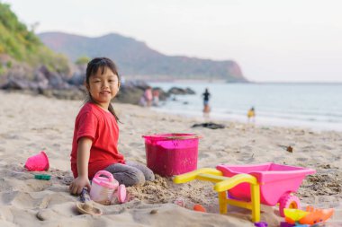 Yaz tatilinde kumsalda oynayan bir çocuk. Çocuklar denizde kumdan kale yapıyorlar..
