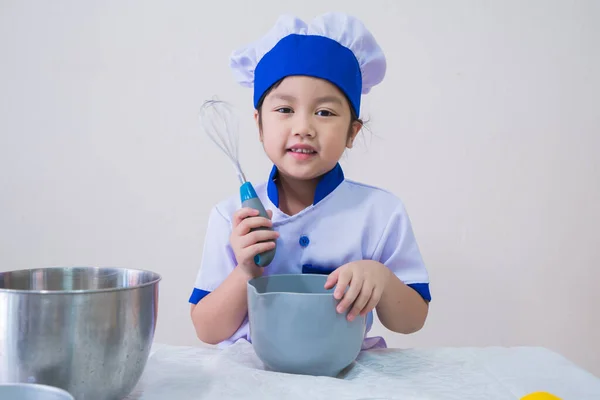 cute girls with amazing smile in clothes and chef cap. Cooking on kitchen cake. Kids make cookie at home, Children do dessert with eggs