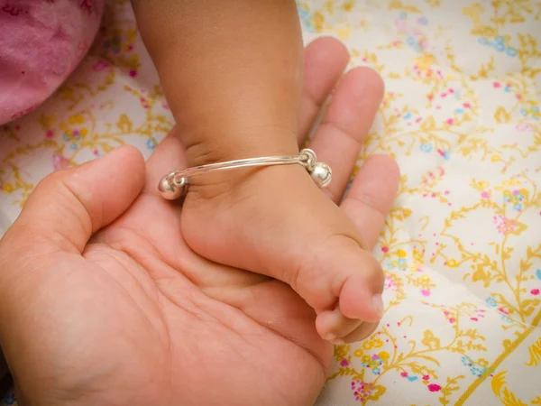 Anklet of newborns in mom's hand — Stock Photo, Image