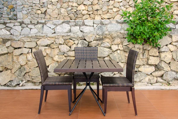Tavolo e sedie in rattan in caffè contro muro di pietra — Foto Stock