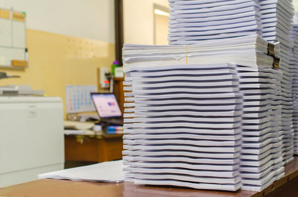 Pile of documents on desk stack up high waiting to be managed