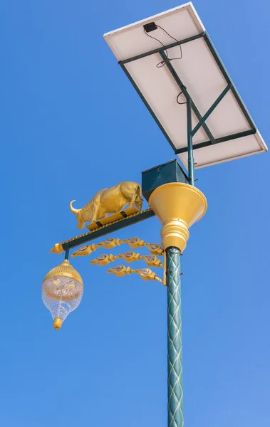 Goldene Kuh Glühbirne und Solarenergie mit blauem Himmel Hintergrund — Stockfoto