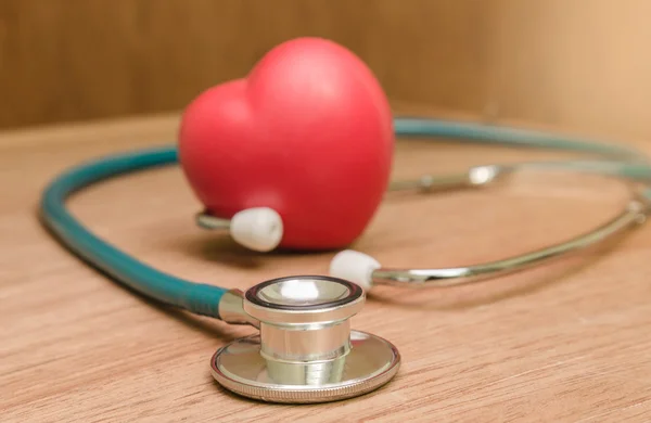 Corazón rojo y estetoscopio sobre fondo de madera . —  Fotos de Stock