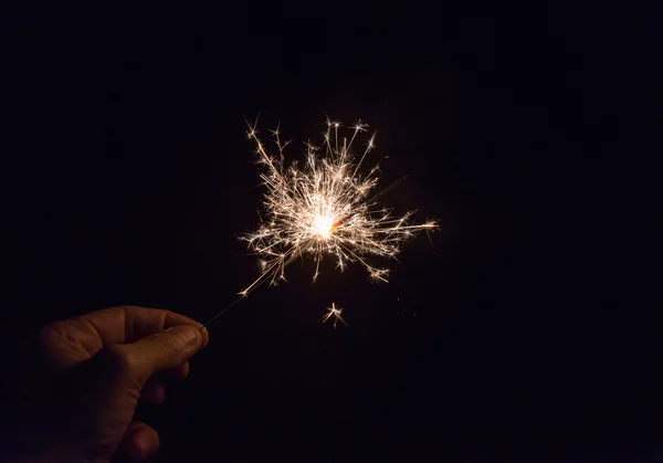 Hand holding a sparkler fire on black background — Stock Photo, Image