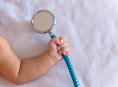 Yeni doğan bebek kız elinde stetoskop tıp aletleri