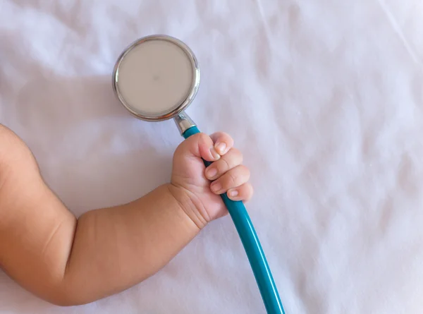 Instrumentos médicos estetoscopio en la mano de la niña recién nacida —  Fotos de Stock