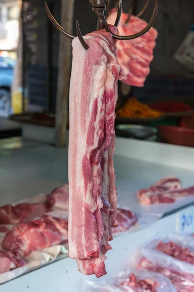 Carne de cerdo colgada de un anzuelo en un mercado — Foto de Stock