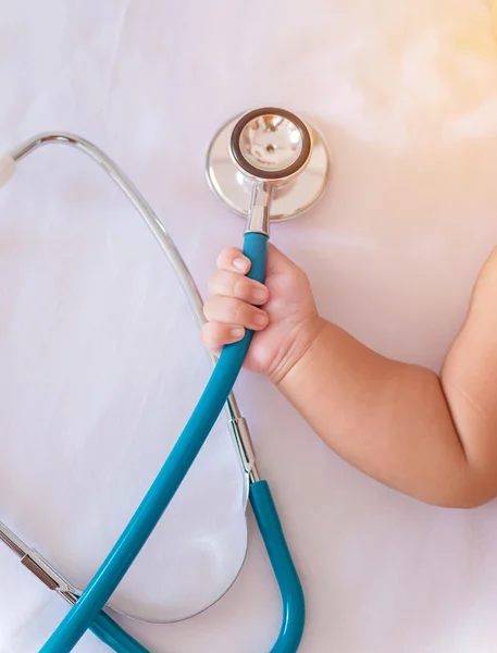 Instrumentos médicos estetoscópio na mão de bebê recém-nascido menina — Fotografia de Stock