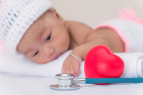 Instrumentos médicos estetoscopio con corazón y bebé niña —  Fotos de Stock