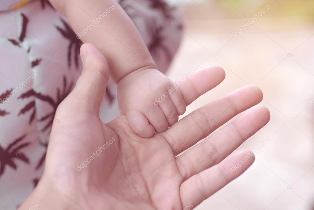Cute newborn baby hand holding mother's finger