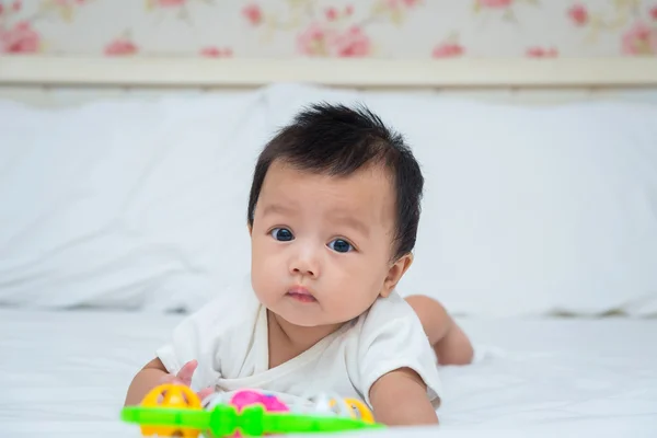 Şirin Bebek kız oyuncakla yatağa portresi — Stok fotoğraf