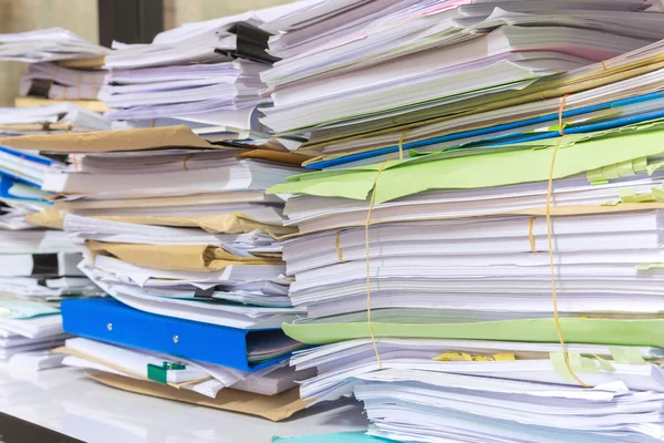 Stapel von Dokumenten auf dem Schreibtisch stapeln sich hoch und warten darauf, verwaltet zu werden — Stockfoto