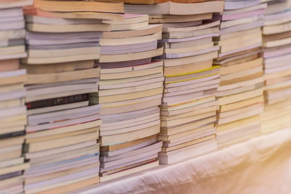 Muitos livros empilham em mesa de madeira na biblioteca — Fotografia de Stock