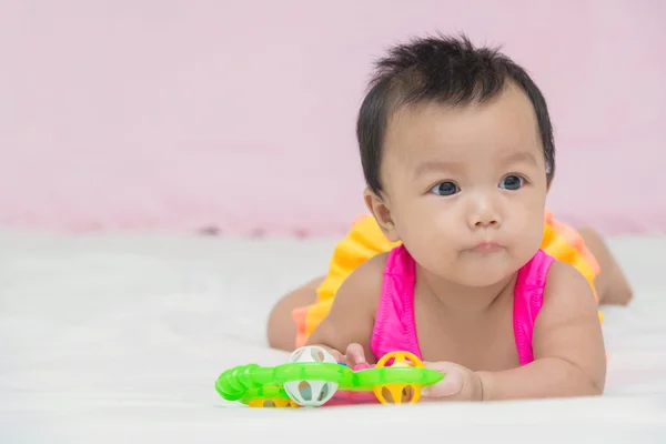 Şirin bebek oyuncak ile yatağa gülümseyen kız portresi — Stok fotoğraf