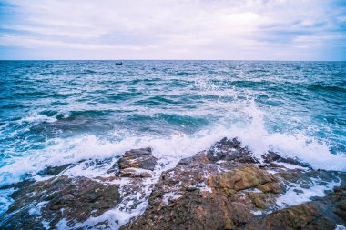 Pürüzsüz Dalgalı Deniz Okyanusu ve mavi gökyüzü ile Kaya Manzarası. Deniz manzaralı tatil zamanı..