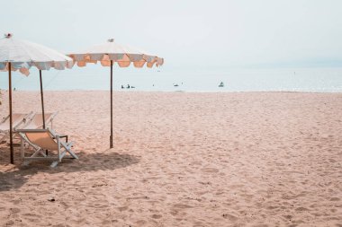 Güverte sandalyeleri ve tropik plajda beyaz şempanzeler. Yazın kumsalda beyaz şemsiye