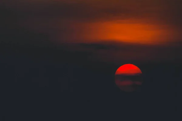 美しい夕日 日没時に雲に囲まれた劇的な火の太陽 鮮やかなオレンジ色の赤い雲が太陽に照らされています — ストック写真