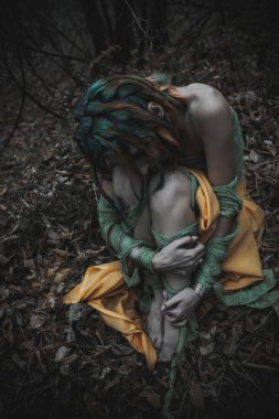 Sonbahar yeşili içinde yeşil ve sarı cüppeli ölü bir kız.