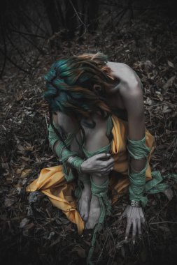Sonbahar yeşili içinde yeşil ve sarı cüppeli ölü bir kız.
