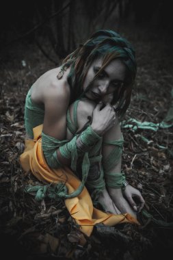 Sonbahar yeşili içinde yeşil ve sarı cüppeli ölü bir kız.
