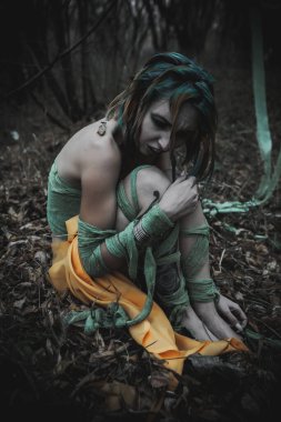 Sonbahar yeşili içinde yeşil ve sarı cüppeli ölü bir kız.