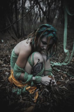 Sonbahar yeşili içinde yeşil ve sarı cüppeli ölü bir kız.