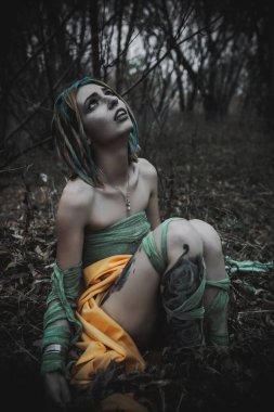 Sonbahar yeşili içinde yeşil ve sarı cüppeli ölü bir kız.