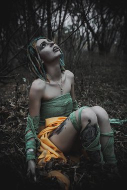 Sonbahar yeşili içinde yeşil ve sarı cüppeli ölü bir kız.