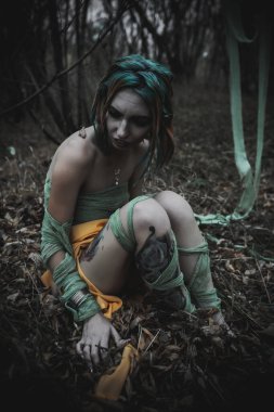 Sonbahar yeşili içinde yeşil ve sarı cüppeli ölü bir kız.