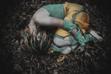 Sonbahar yeşili içinde yeşil ve sarı cüppeli ölü bir kız.