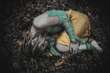 Sonbahar yeşili içinde yeşil ve sarı cüppeli ölü bir kız.