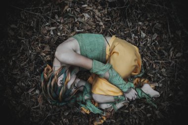 Sonbahar yeşili içinde yeşil ve sarı cüppeli ölü bir kız.