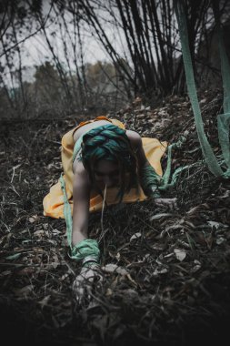 Sonbahar yeşili içinde yeşil ve sarı cüppeli ölü bir kız.