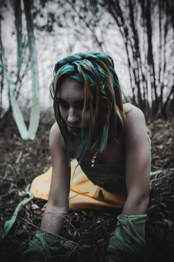 Sonbahar yeşili içinde yeşil ve sarı cüppeli ölü bir kız.