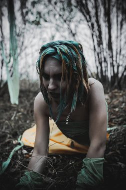 Sonbahar yeşili içinde yeşil ve sarı cüppeli ölü bir kız.